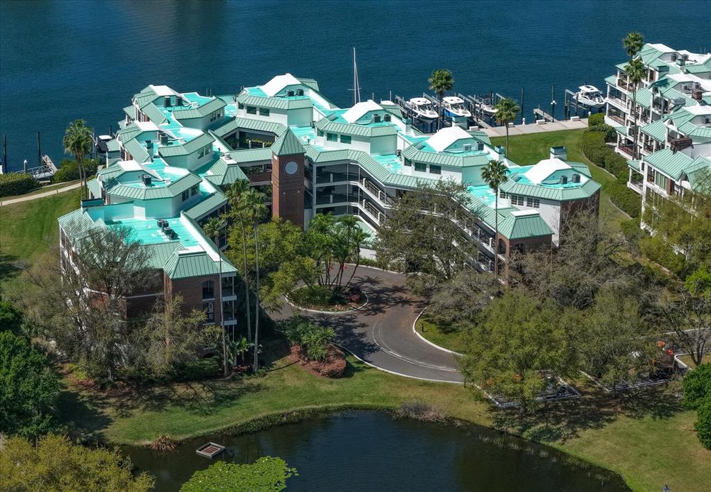 An aerial view shows a multi-story waterfront apartment complex with green roofs and boat slips — 947 SEDDON COVE WAY UNIT 947, TAMPA, FL