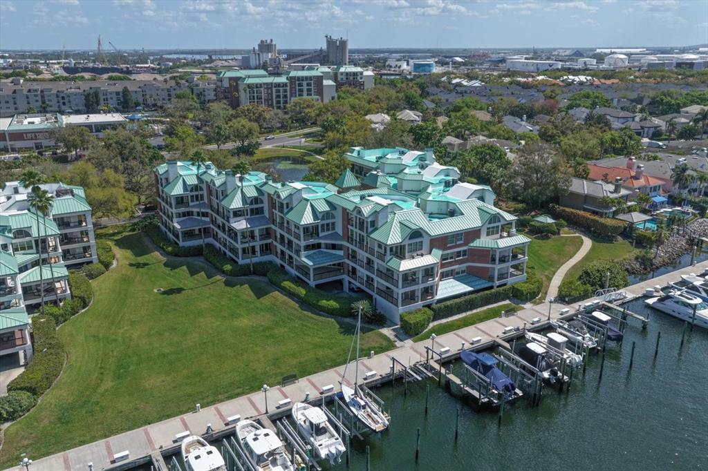 An aerial view shows a multi-story waterfront condominium complex with green roofs and boat slips — 947 SEDDON COVE WAY UNIT 947, TAMPA, FL
