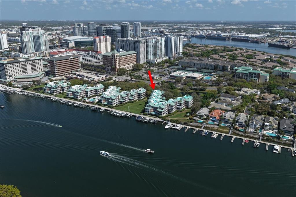 An aerial view shows a waterfront condominium complex with a red arrow pointing toward it — 947 SEDDON COVE WAY UNIT 947, TAMPA, FL