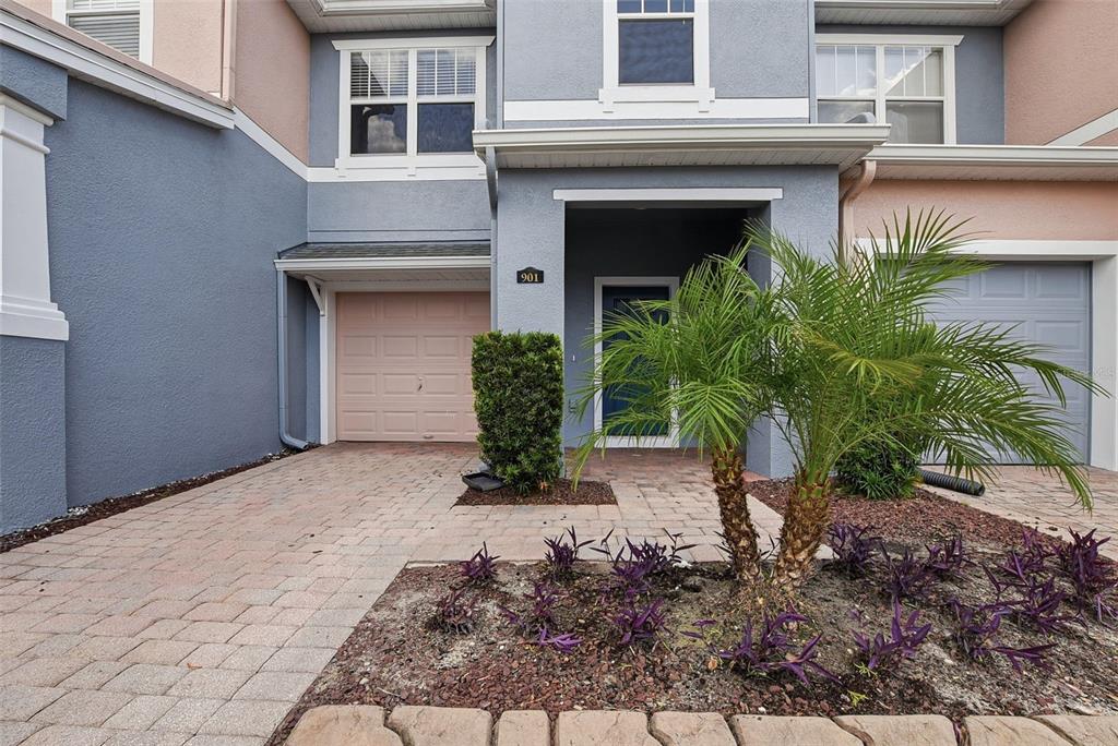 A two-story townhouse exterior features a pink garage door, a front entrance, and a palm tree — 901 PINE POINTE LANE, ORLANDO, FL