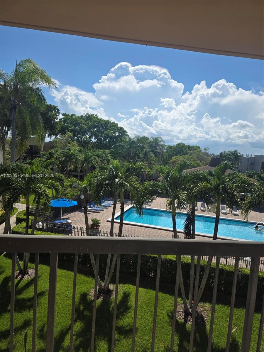 An elevated view from a balcony overlooks a swimming pool surrounded by palm trees — 10985 SW 107th St # 312, Miami FL 33176, MIAMI, FL