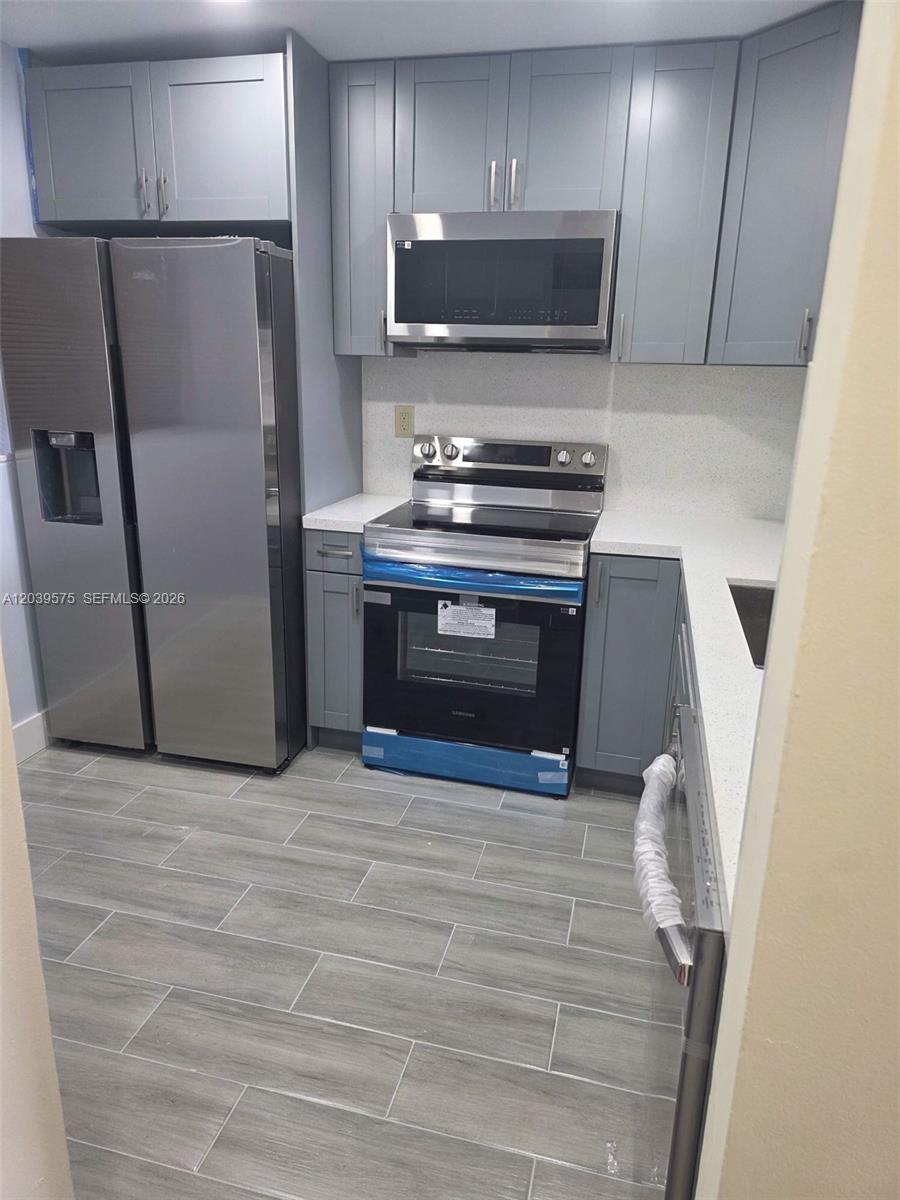 A kitchen features gray cabinets, stainless steel appliances, and light-colored countertops — 10985 SW 107th St # 312, Miami FL 33176, MIAMI, FL