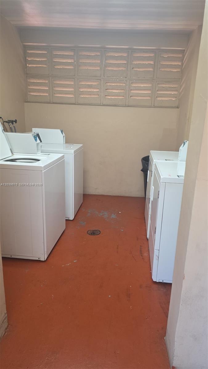 A laundry room contains two white washing machines and two white dryers on a red floor — 10985 SW 107th St # 312, Miami FL 33176, MIAMI, FL
