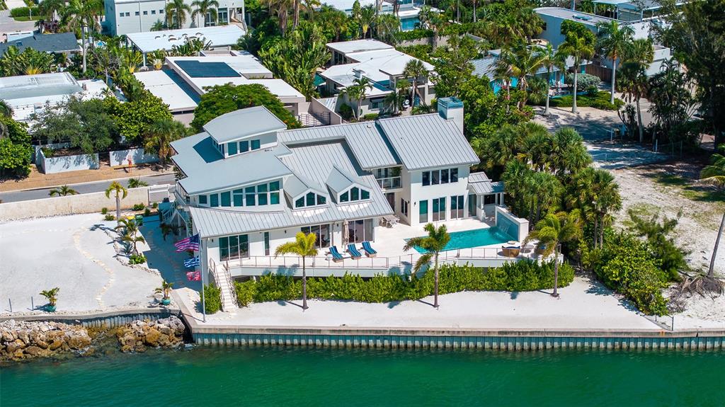 An aerial view of a modern waterfront house featuring a pool, deck, and metal roof — 1209 WESTWAY DRIVE, SARASOTA, FL