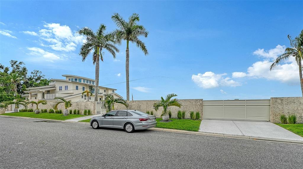 A silver sedan is parked on a street in front of a walled residential property — 1209 WESTWAY DRIVE, SARASOTA, FL