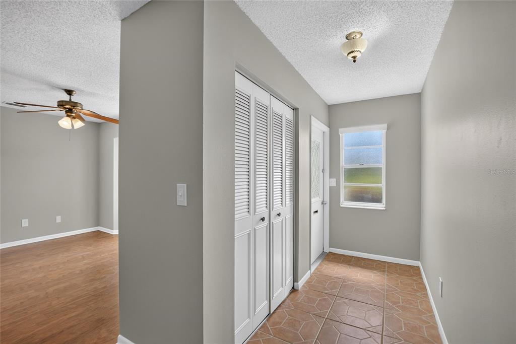 An entryway with tiled flooring, a white louvered closet, and an adjacent room with wood-look flooring — 1244 W DEL WEBB BOULEVARD, SUN CITY CENTER, FL