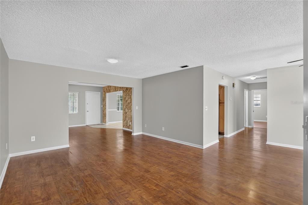 An empty living area features light gray walls, wood-look flooring, and a textured ceiling — 1244 W DEL WEBB BOULEVARD, SUN CITY CENTER, FL