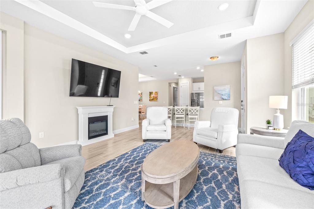 A living room features a fireplace, a blue patterned rug, and an open kitchen area — 4639 GAROFALO ROAD, WESLEY CHAPEL, FL