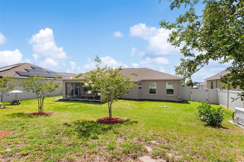 The backyard of a single-story house features a screened-in patio, lawn, and vinyl fencing — 444 LAKE VIEW WAY, AUBURNDALE, FL