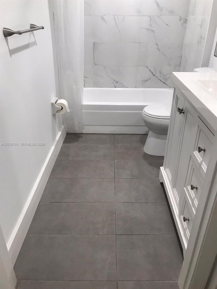An empty living room features dark tile flooring, a ceiling fan, and a sliding glass door — 462 NE 210th Cir Ter # 9, Miami FL 33179, MIAMI, FL