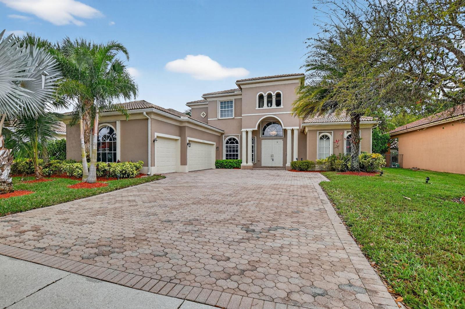 A two-story tan stucco house with a paver driveway and a three-car garage — 6039 Walnut Hill Drive, Lake Worth FL 33467, LAKE WORTH, FL