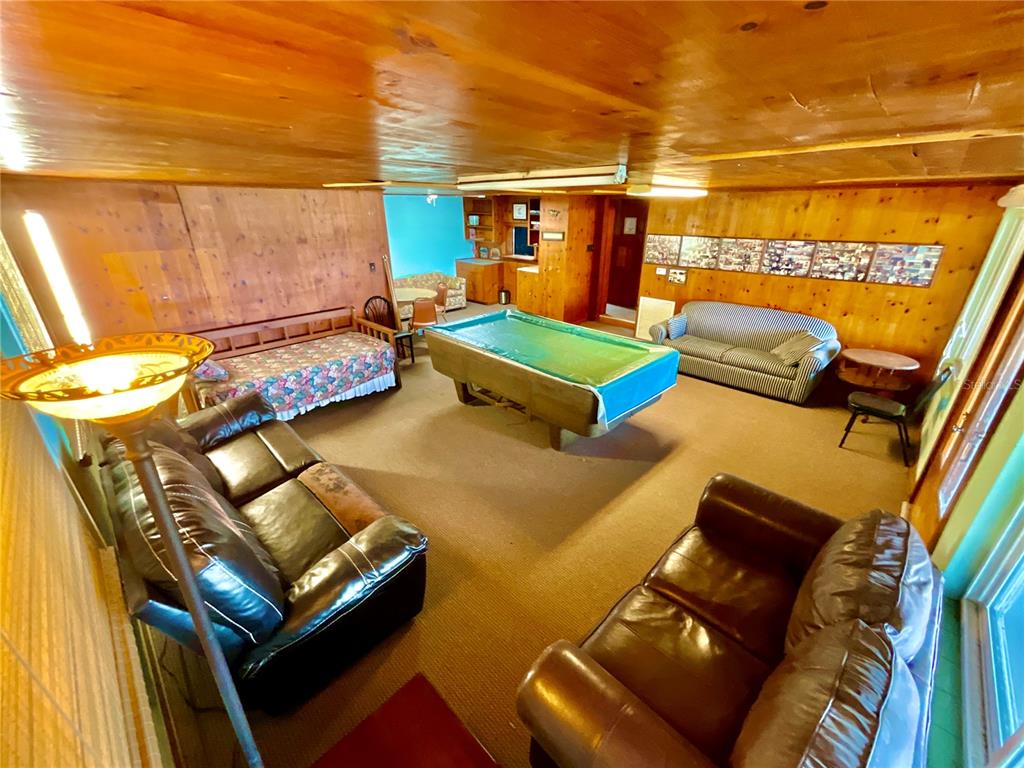 A wood-paneled recreation room features a pool table, two leather sofas, and a daybed — 106 E SUNNYSIDE BEACH ROAD, HAWTHORNE, FL