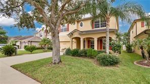 A two-story beige house with a front lawn, a large tree, and a palm tree — 9068 VICKROY TERRACE, OVIEDO, FL