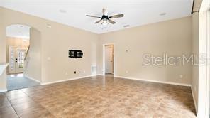 An open living area features tan tile flooring, a ceiling fan, and an arched entryway — 9068 VICKROY TERRACE, OVIEDO, FL