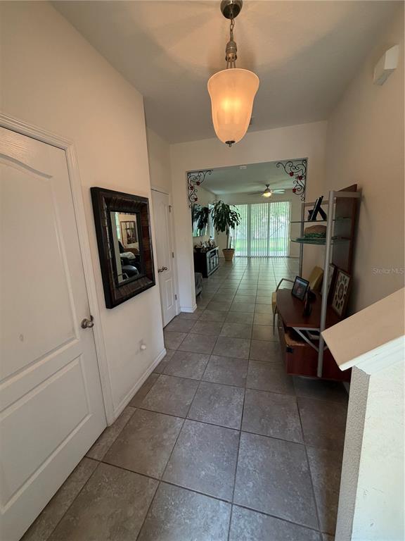 A tiled entryway leads into a living area with a pendant light and wall mirror — 6305 SUNSAIL PLACE, APOLLO BEACH, FL