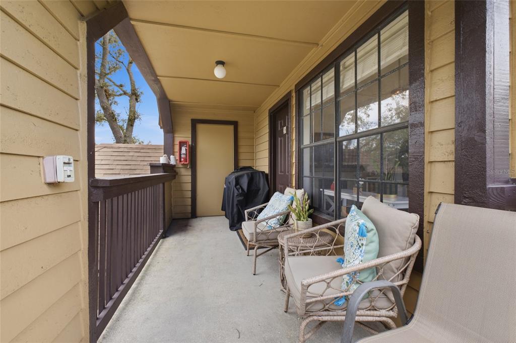 A covered balcony features tan siding, a concrete floor, two wicker chairs, and a grill — 364 NORTHPOINTE COURT UNIT 208, ALTAMONTE SPRINGS, FL