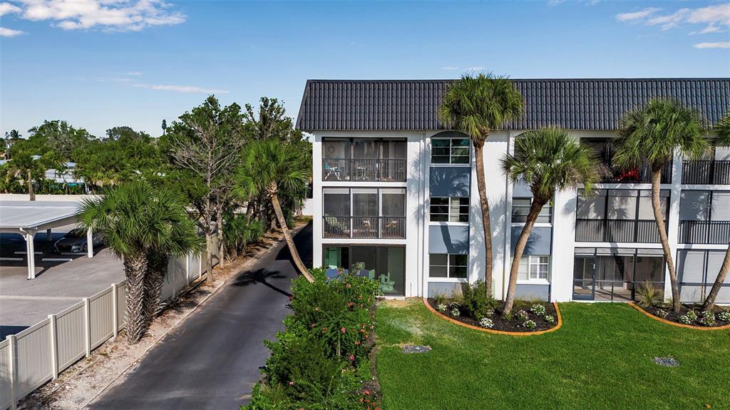 An exterior view of a multi-story apartment building with screened balconies and palm trees — 5600 BEACH WAY DRIVE UNIT 201, SARASOTA, FL