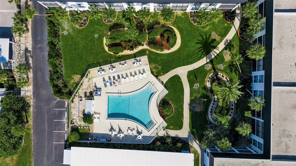 An aerial view shows a swimming pool with lounge chairs surrounded by landscaping and buildings — 5600 BEACH WAY DRIVE UNIT 201, SARASOTA, FL