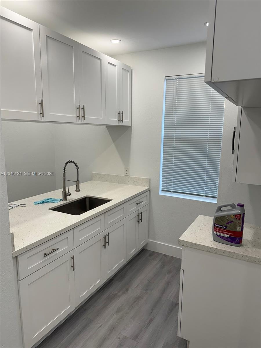 A laundry room features white shaker cabinets, quartz countertops, a stainless sink, and gray flooring — 1450 SW 4th St # 2, Miami FL 33135, MIAMI, FL