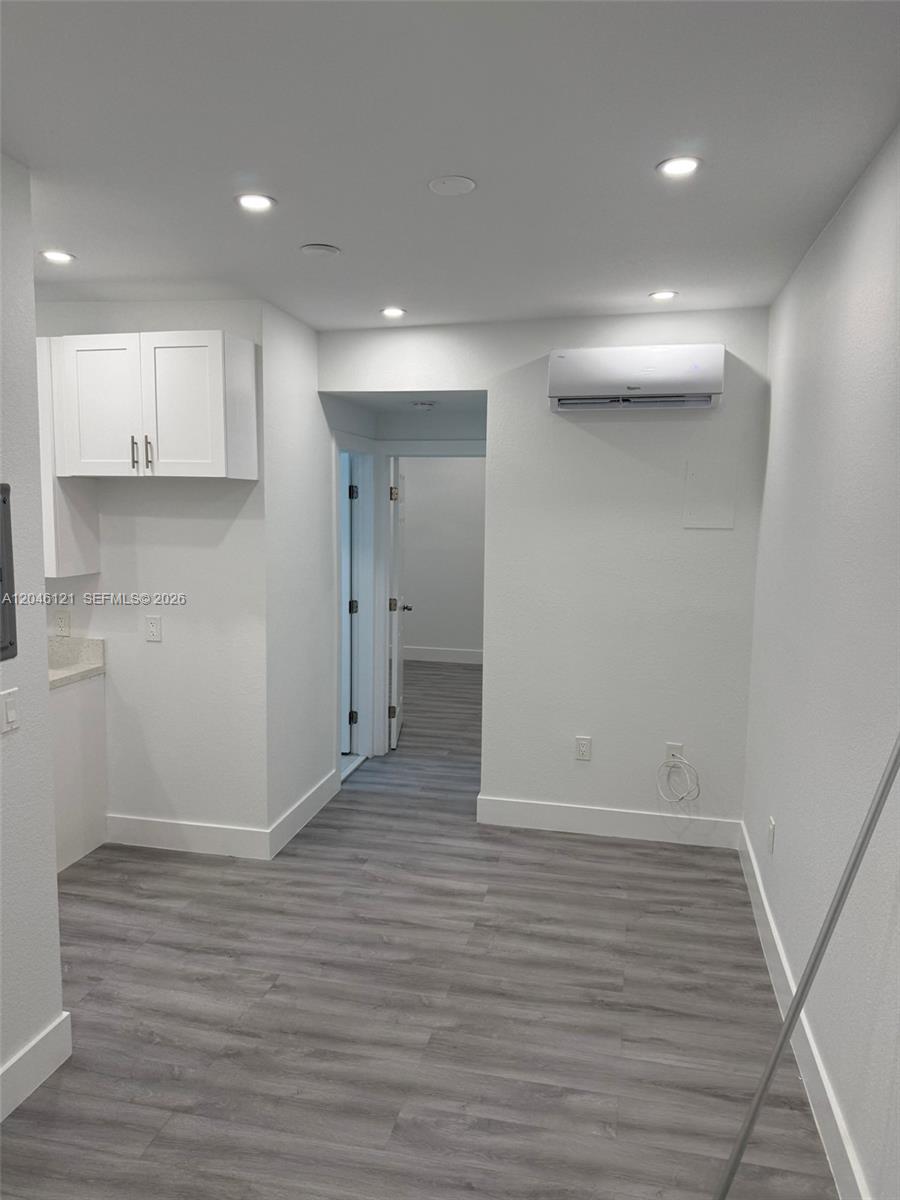 A room with white walls, gray wood-look flooring, a wall-mounted air conditioner, and white cabinets — 1450 SW 4th St # 2, Miami FL 33135, MIAMI, FL