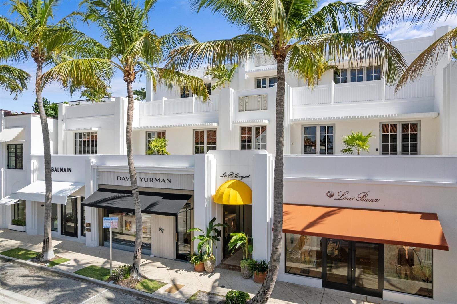 An exterior view of a white multi-story commercial building with palm trees and retail storefronts — 247 Worth Avenue, Palm Beach FL 33480, PALM BEACH, FL