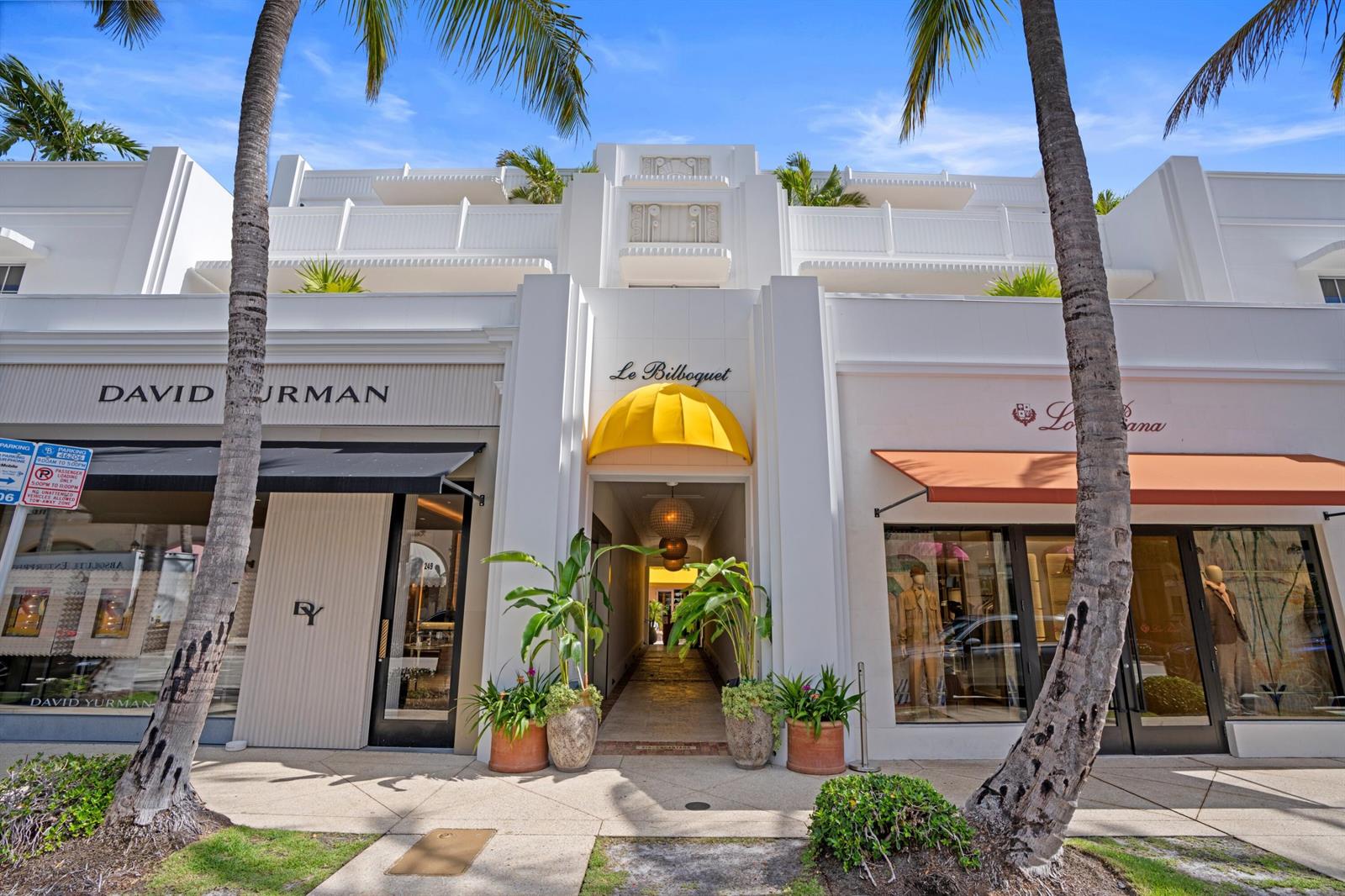The exterior of a white building features a central yellow awning and two storefronts — 247 Worth Avenue, Palm Beach FL 33480, PALM BEACH, FL