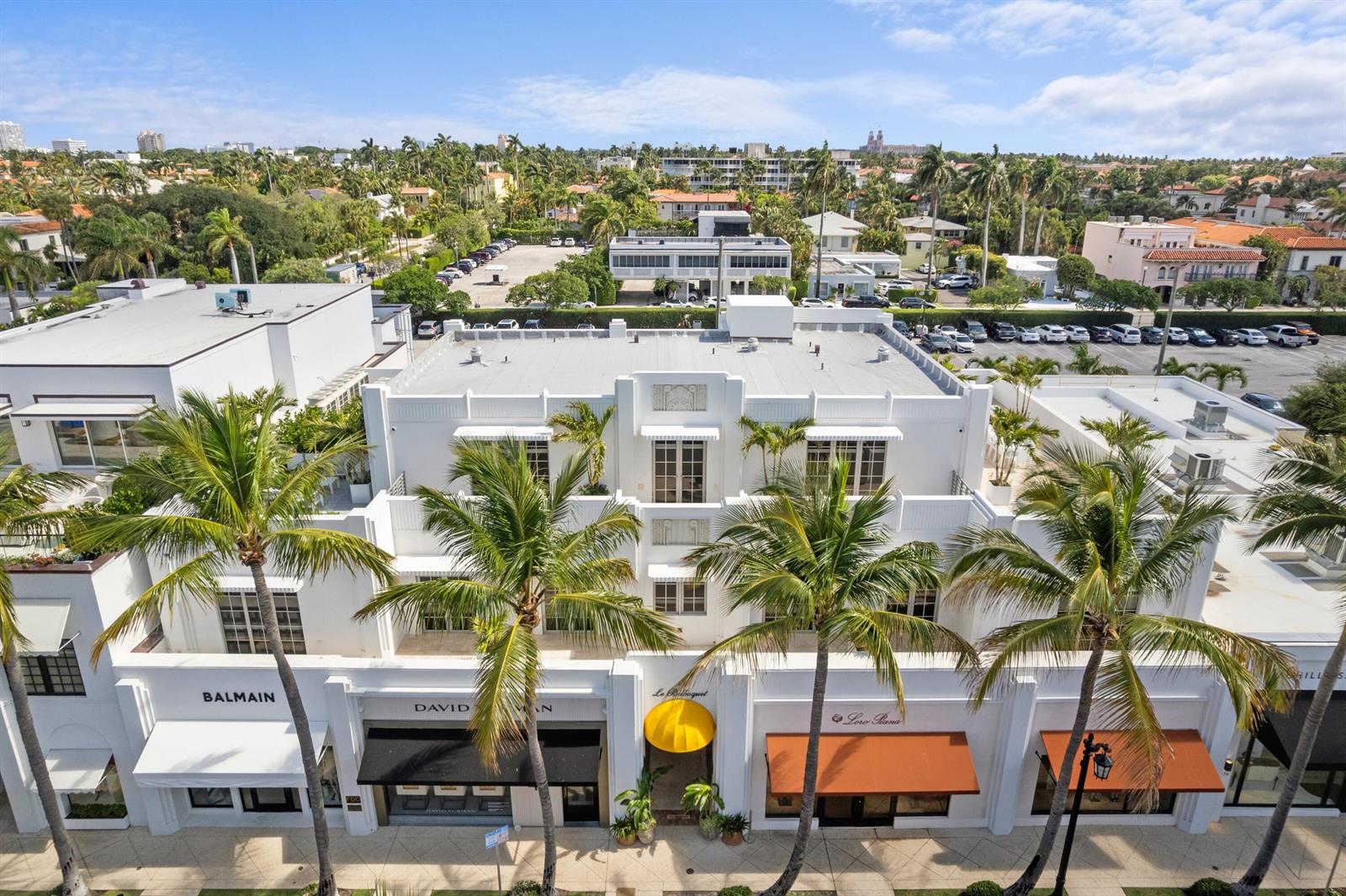 An aerial view of a white multi-story commercial building with palm trees and storefronts — 247 Worth Avenue, Palm Beach FL 33480, PALM BEACH, FL