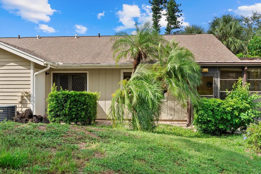 The exterior of a single-story house features beige siding, a shingled roof, and palm trees — 3001 SEAWIND CIRCLE UNIT 10C, VENICE, FL