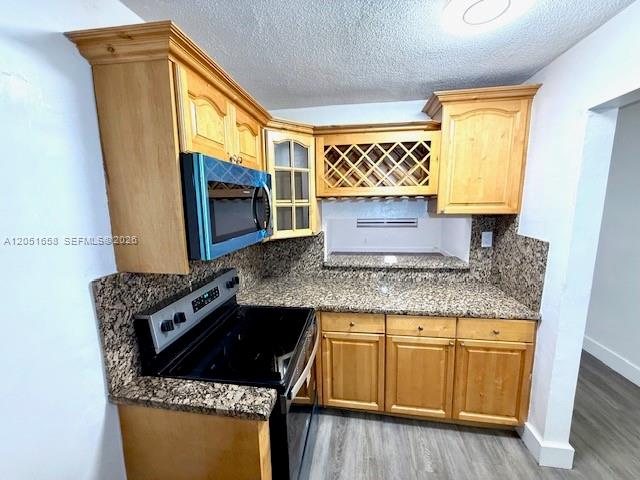 A kitchen features light wood cabinets, granite countertops, and a black microwave and stove — 1945 NW 29th St # A8, Miami FL 33142, MIAMI, FL