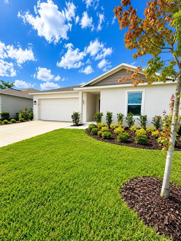 A single-story house with a white exterior, a two-car garage, and a landscaped front yard — 1322 INKBERRY CIRCLE, DELAND, FL