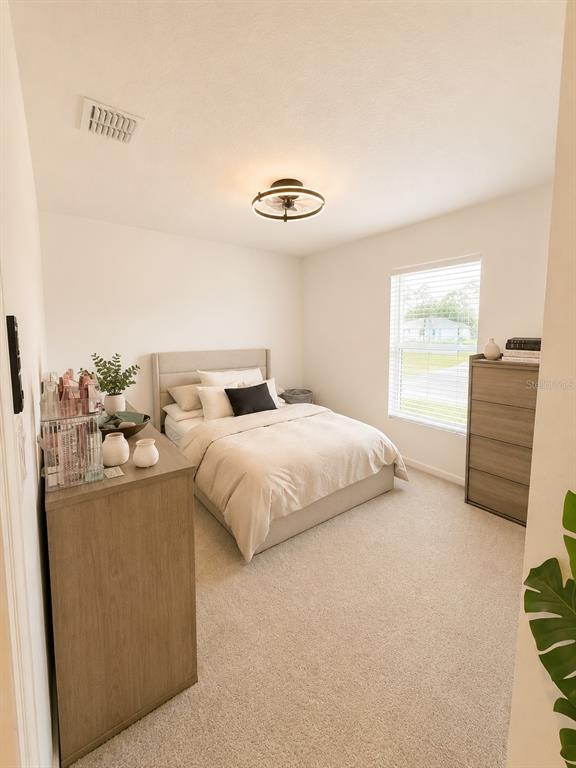 A bedroom features a bed with neutral bedding, a dresser, and a ceiling fan light — 1322 INKBERRY CIRCLE, DELAND, FL