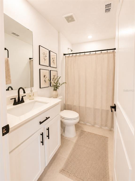 A bathroom features a white vanity, a toilet, and a shower with a beige curtain — 1322 INKBERRY CIRCLE, DELAND, FL