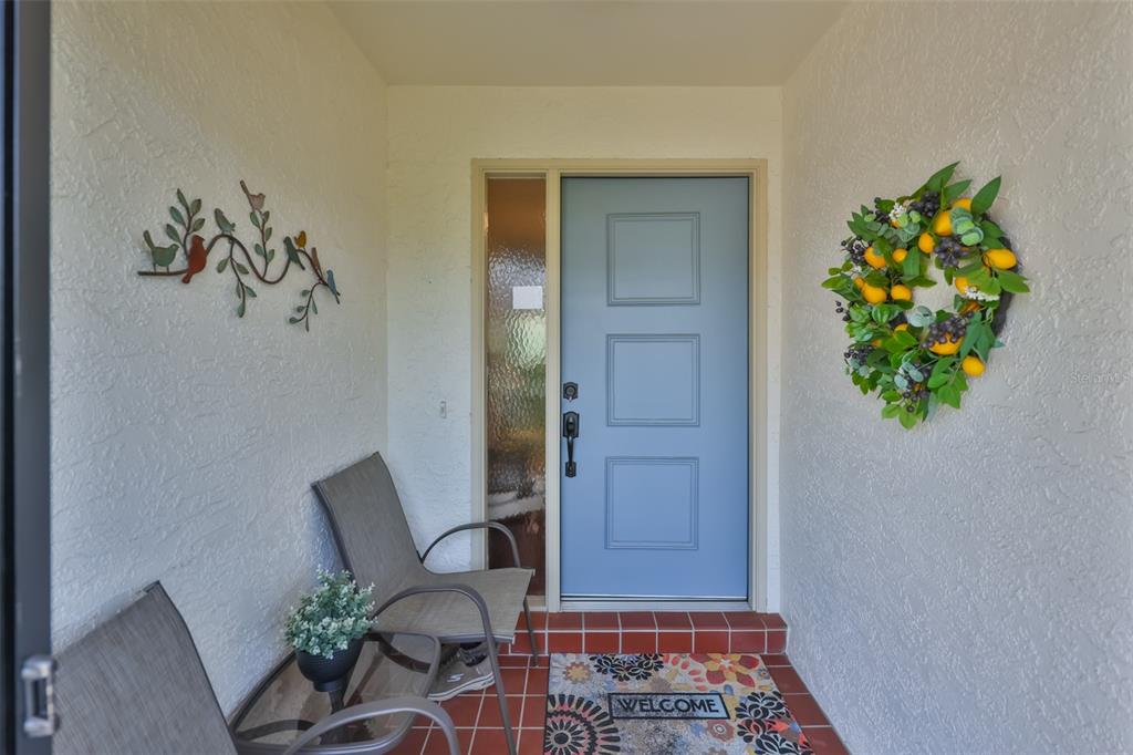 A light blue front door with a side window opens onto a tiled entryway porch — 2417 LANCASTER DRIVE, SUN CITY CENTER, FL