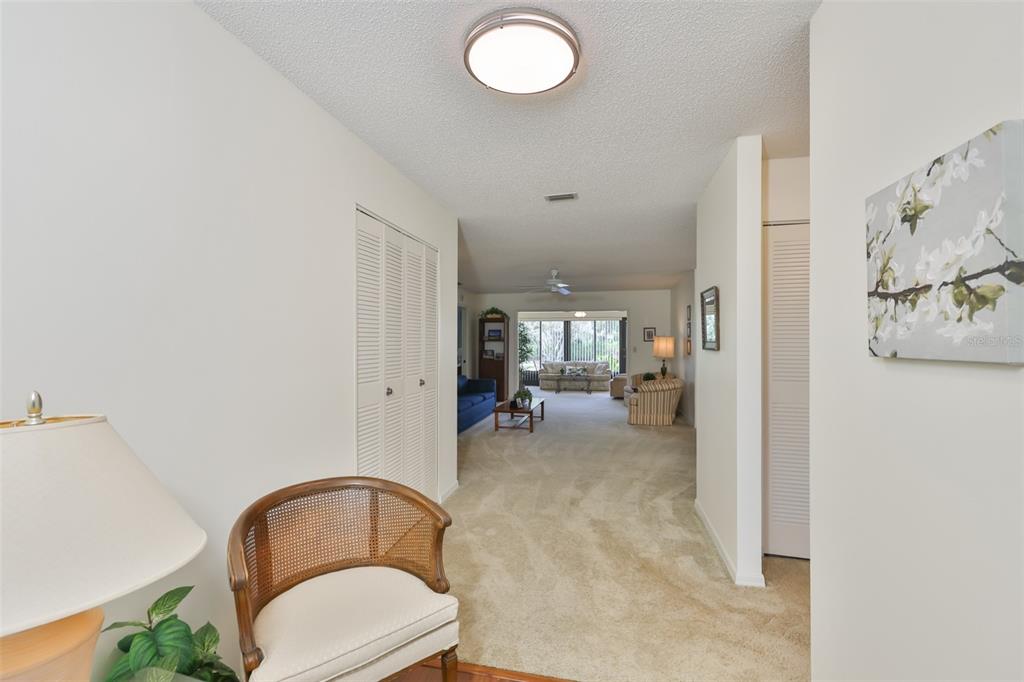 A view from a hallway looking into a carpeted living room with a ceiling fan — 2417 LANCASTER DRIVE, SUN CITY CENTER, FL