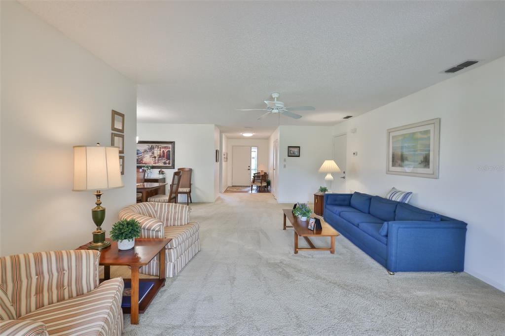 A living room with beige carpet, a blue sofa, and striped armchairs — 2417 LANCASTER DRIVE, SUN CITY CENTER, FL