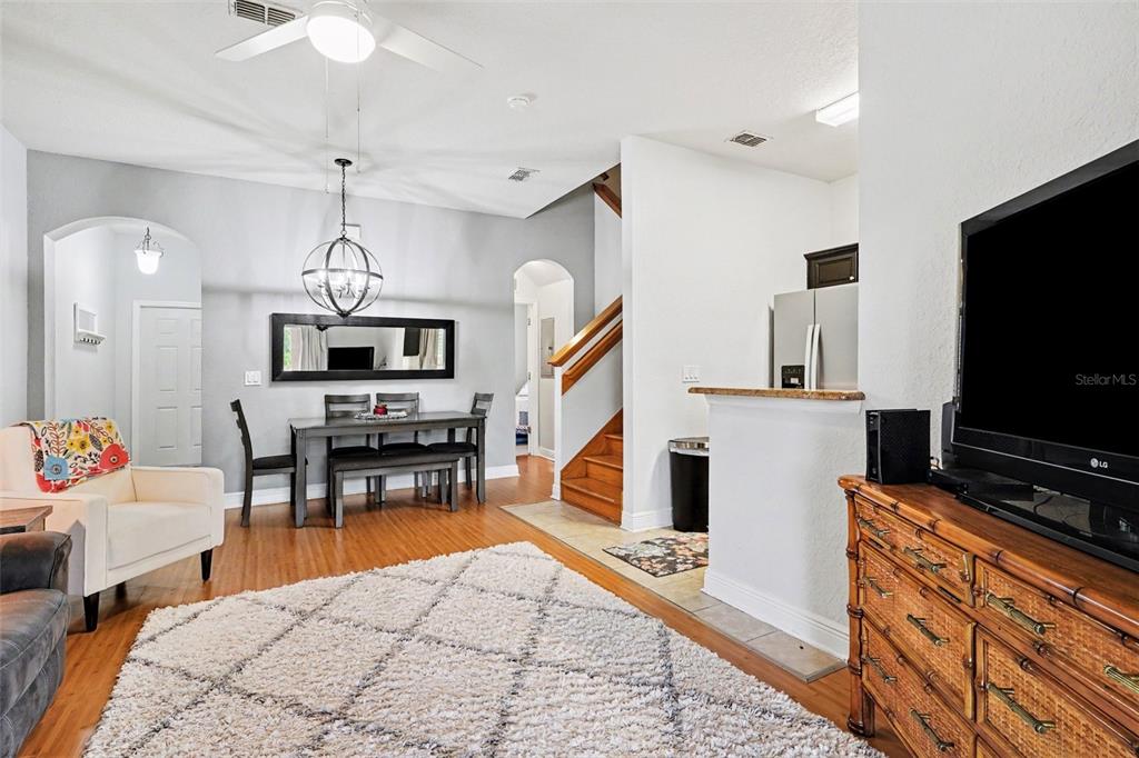 A living and dining area features hardwood floors, a white rug, and a wooden staircase — 3428 CALABRIA AVE, DAVENPORT, FL