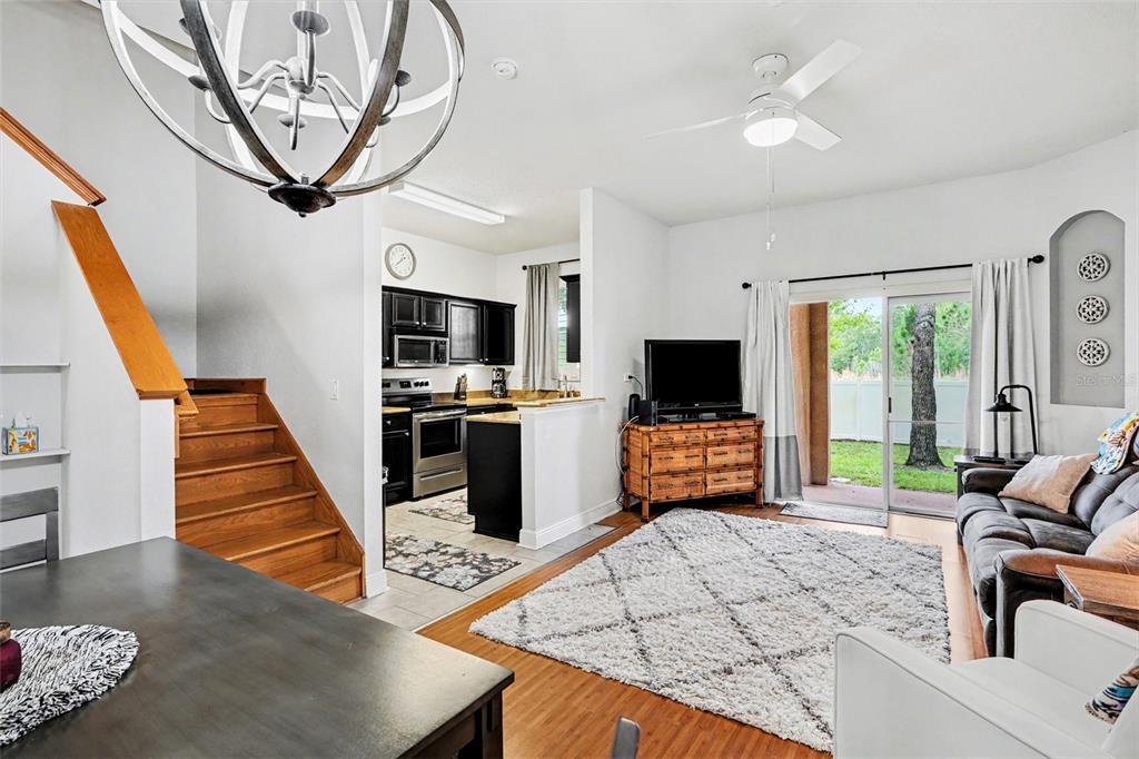 An open-concept living room features wood flooring, a staircase, and an adjacent kitchen with cabinets — 3428 CALABRIA AVE, DAVENPORT, FL
