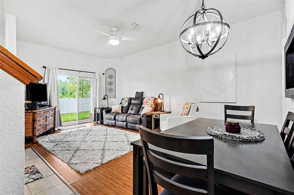 A living and dining area features a dark sofa, a dining table, and sliding glass doors — 3428 CALABRIA AVE, DAVENPORT, FL