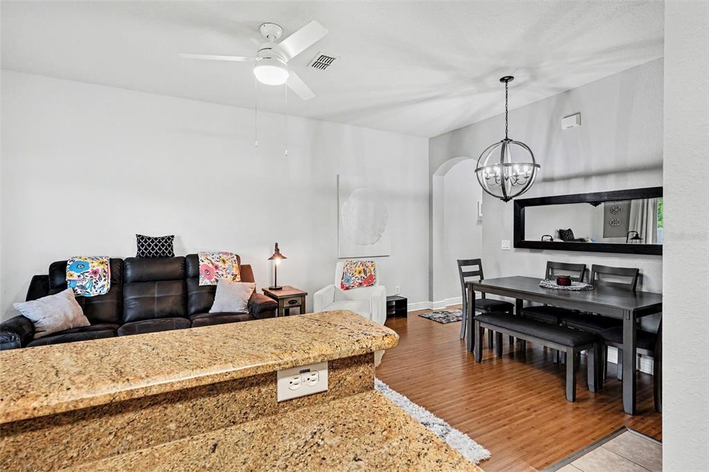 A living and dining area features a granite kitchen island, dark leather sofa, and dining set — 3428 CALABRIA AVE, DAVENPORT, FL