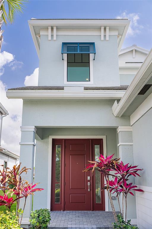 A light blue house exterior features a red front door and a small upper window — 217 SE FASCINO CIRCLE, PORT ST LUCIE, FL