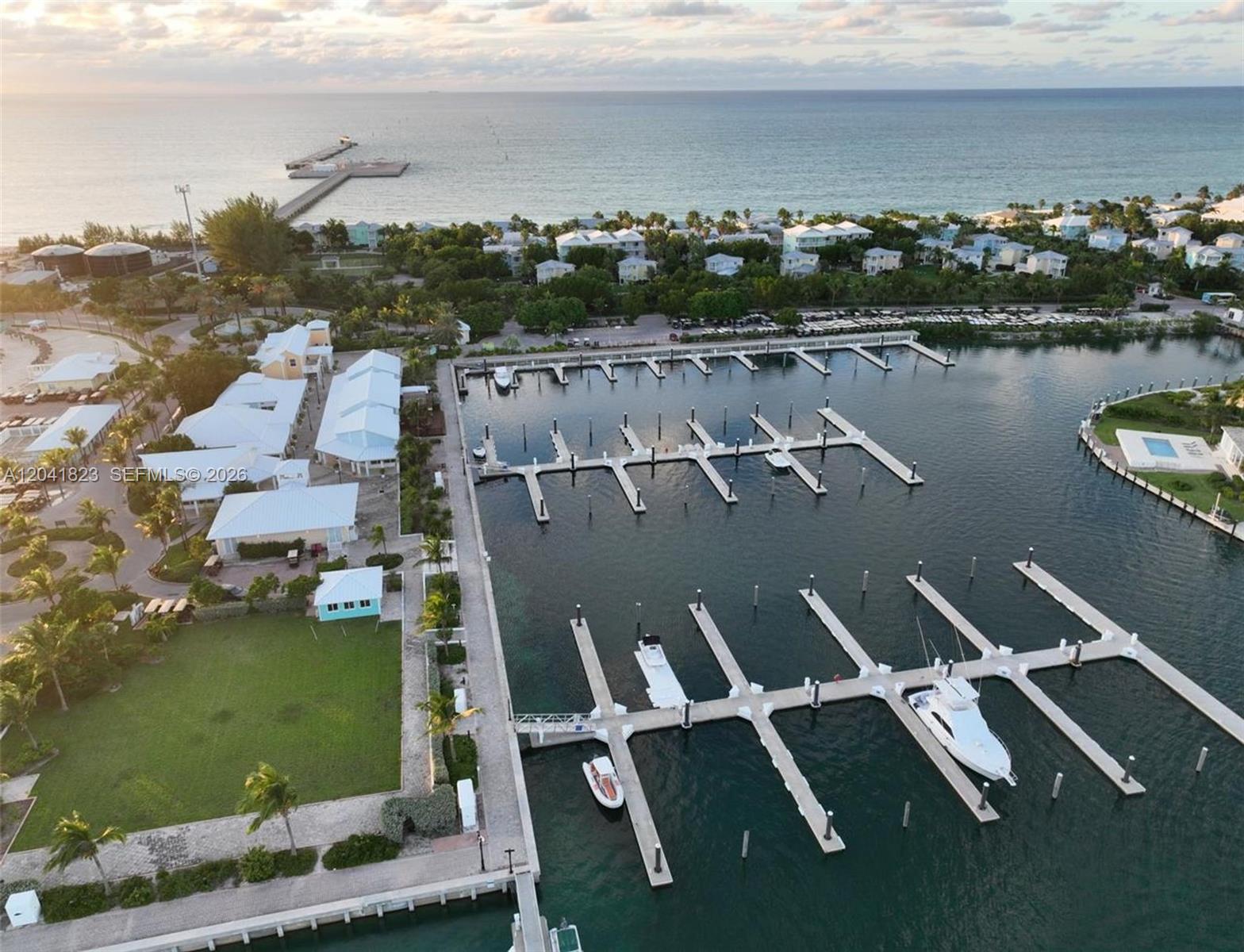 An aerial view shows a marina with multiple boat slips, docks, and nearby coastal buildings — 65A Bimini Bay Resort # 302, FL, FL