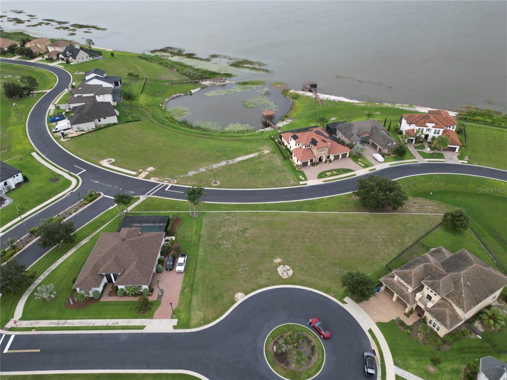 An aerial view shows several houses, a cul-de-sac, and a small pond near a lake — 210 SPRING AZURE DRIVE, LAKE ALFRED, FL