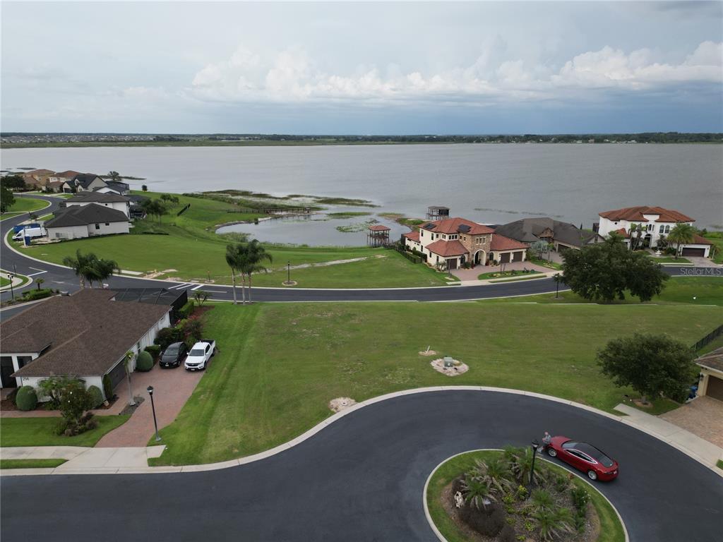An aerial view shows a residential neighborhood with houses, a cul-de-sac, and a large lake — 210 SPRING AZURE DRIVE, LAKE ALFRED, FL