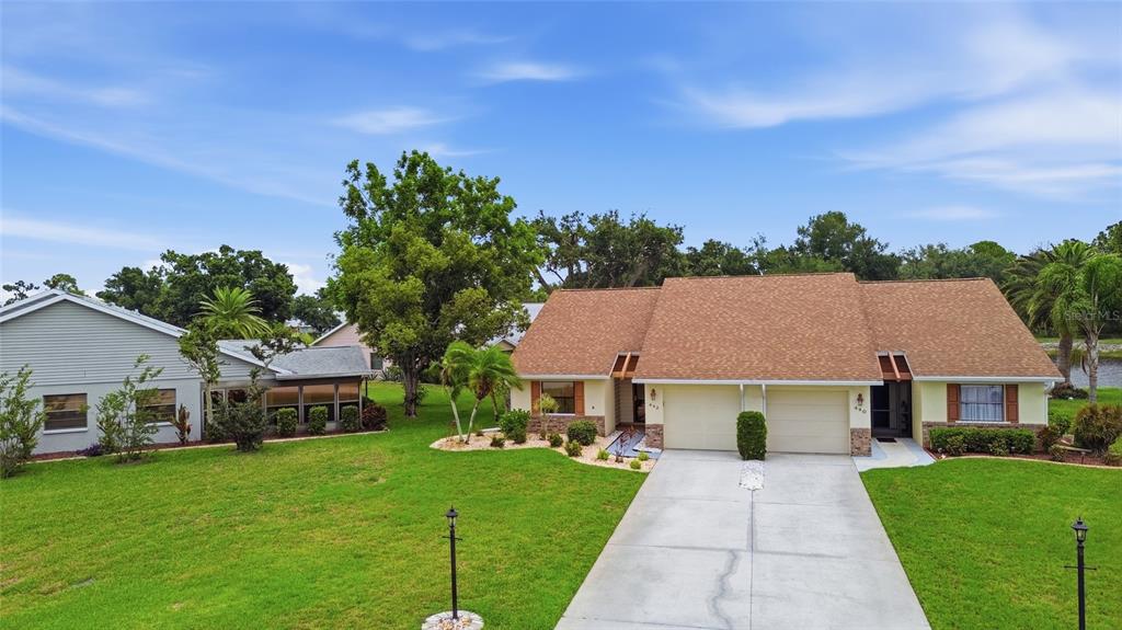 A duplex house with a tan exterior, brown shingled roof, and a shared concrete driveway — 442 PENDLETON DRIVE, VENICE, FL