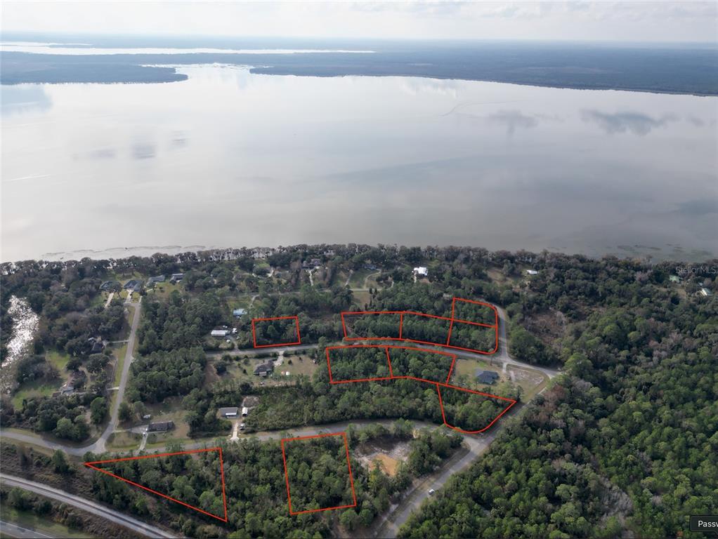 An aerial view shows several wooded residential lots outlined in red near a large lake — 202ND TERRACE, HAWTHORNE, FL