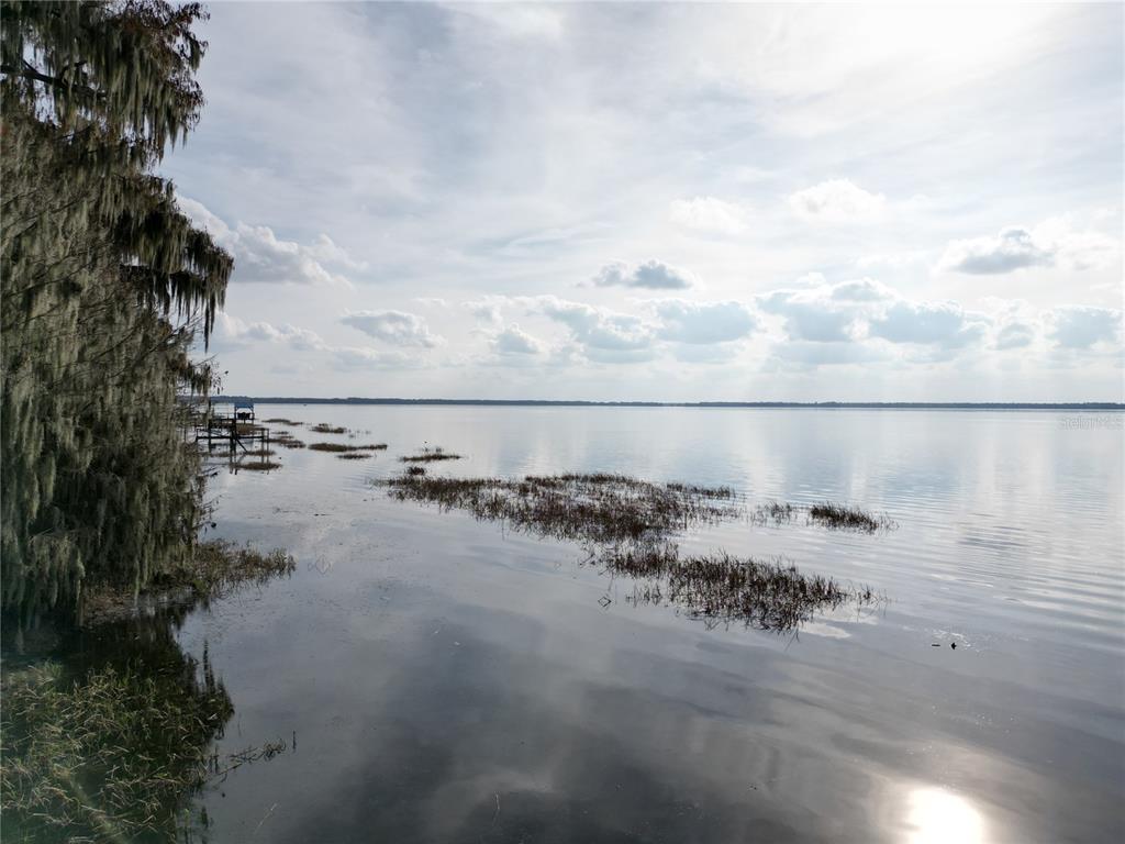 A view of a calm lake with a grassy shoreline and a small wooden dock — 202ND TERRACE, HAWTHORNE, FL