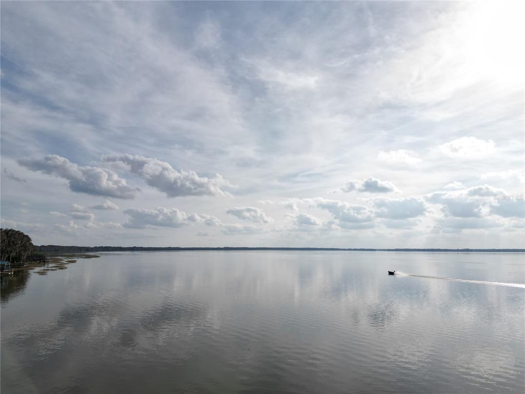 A small boat travels across a large, calm lake under a cloudy sky — 202ND TERRACE, HAWTHORNE, FL