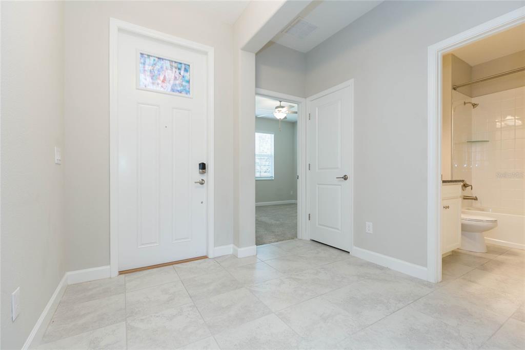 A tiled entryway features a white front door, a closed interior door, and an adjacent bathroom — 31726 CABANA RYE AVENUE, SAN ANTONIO, FL