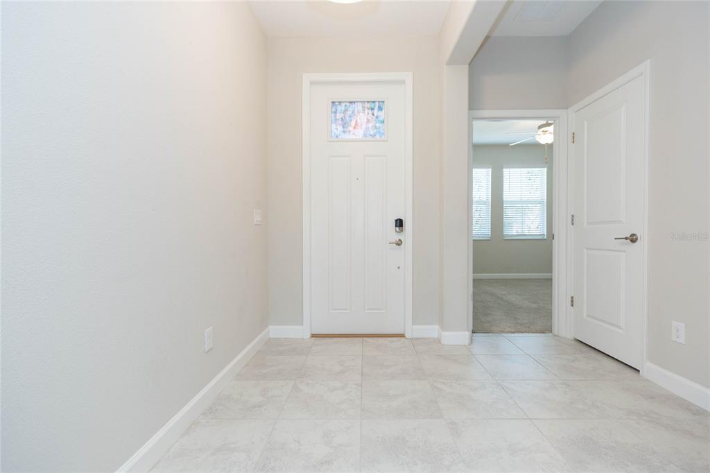 A tiled entryway features a white front door and a doorway leading to a room — 31726 CABANA RYE AVENUE, SAN ANTONIO, FL