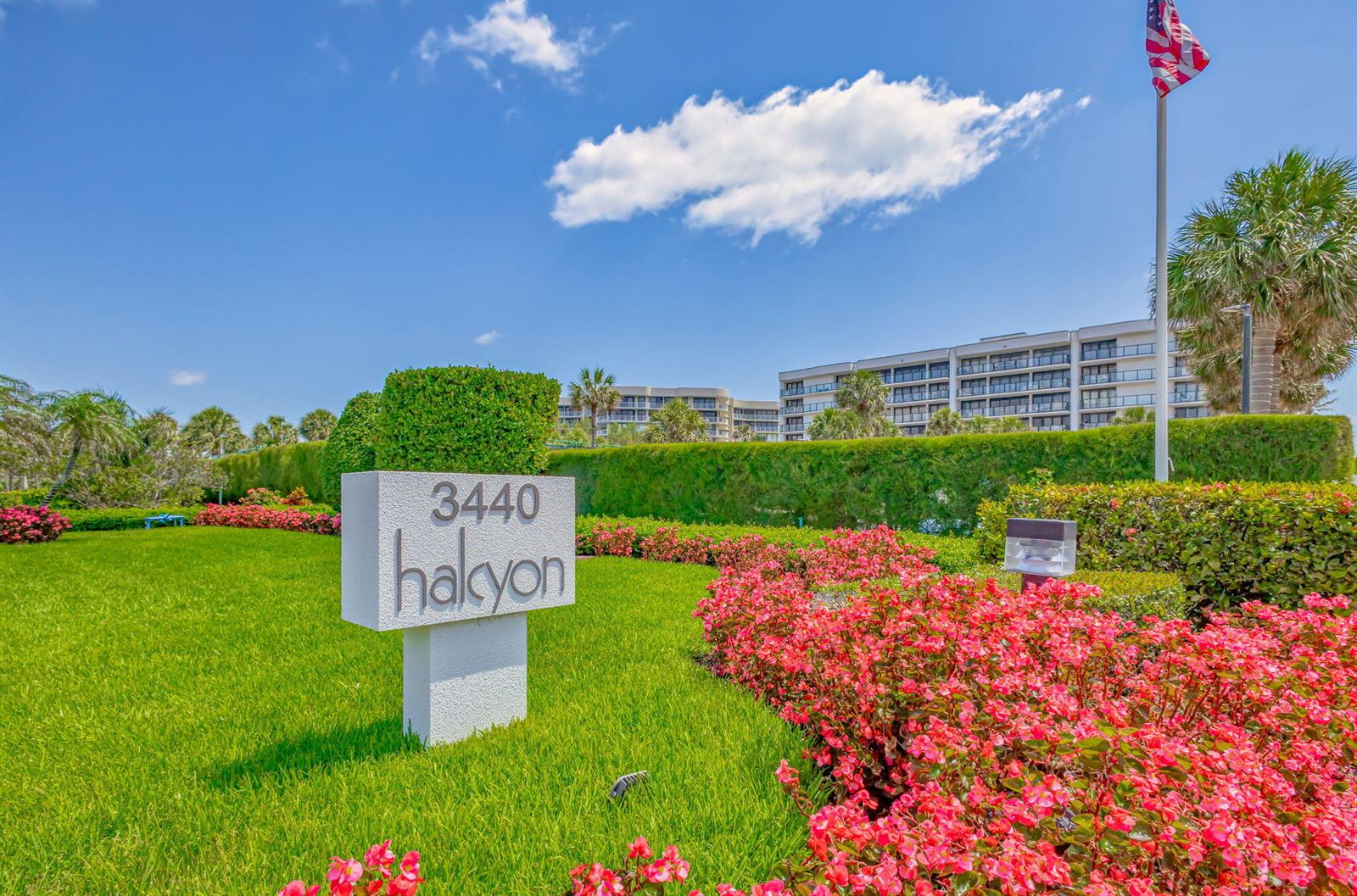 A white sign with the text 3440 halcyon stands in a garden with red flowers — 3440 S Ocean Boulevard # 204s, Palm Beach FL 33480, PALM BEACH, FL